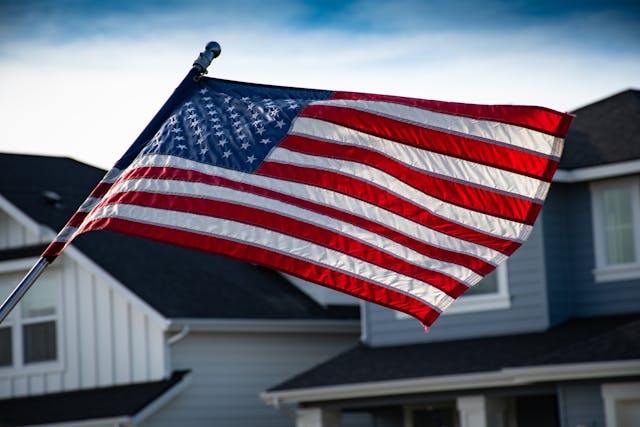 american flag flying near houses and blue sky