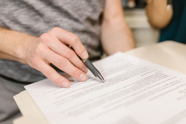 someones hand holding a pen reviewing a document
